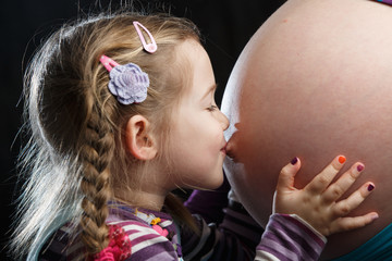 Girl kissing pregnant belly