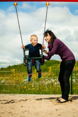 Mother and son having fun on a swing outside