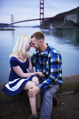 Fototapeta premium romantic couple cuddling by golden gate bridge at dusk