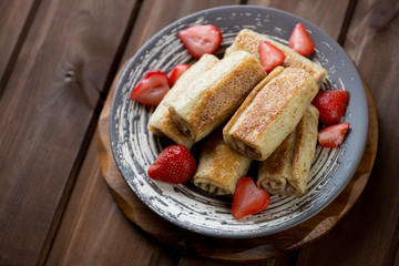 Strawberry stuffed pancakes over dark wooden background