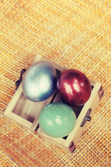 Colorful easter eggs in small wood case on bamboo weave sheet ba
