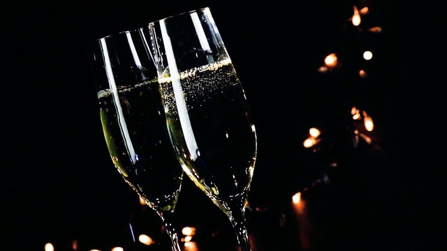 champagne flutes with golden bubbles on dark light background