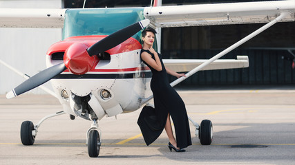 Beautiful woman fashion portrait next to airplane.