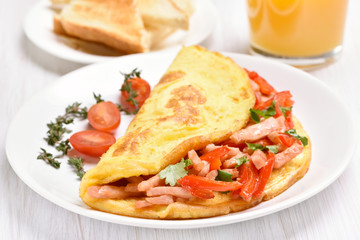 Egg omelette with vegetables and ham on white plate