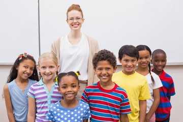 Obraz premium Teacher and pupils smiling at camera in classroom