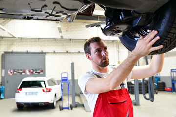KFZ Mechaniker kontrolliert Reifen in der Autowerkstatt