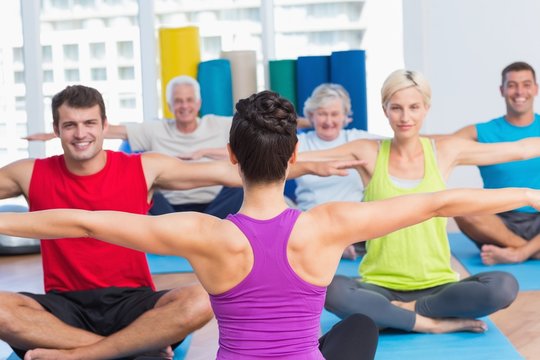 People practicing yoga in health club