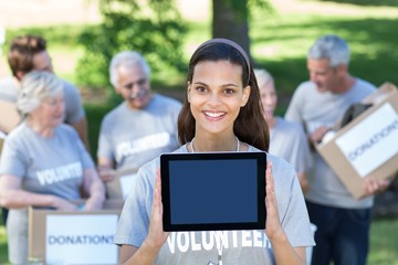 Smiling volunteer brunette showing tablet pc screen