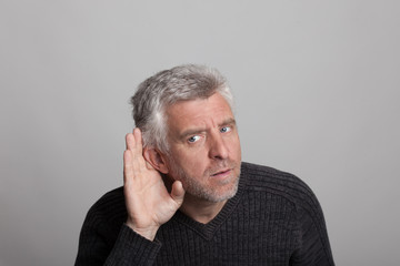 Obraz premium aged man listens with his hand to his ear