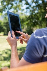 Young man using tablet on park bench