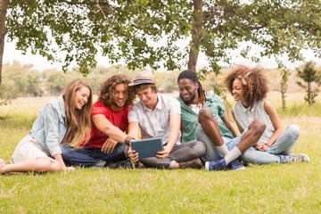 Happy friends in the park looking at tablet