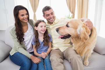 Family looking at Golden Retriever on sofa