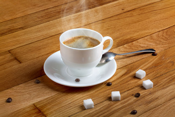 Hot fresh coffee in a white cup with sugar on wooden table