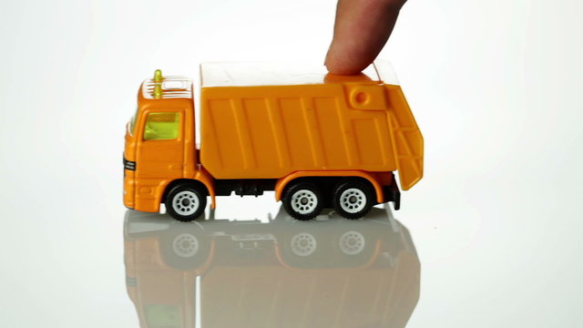 Orange toy garbage truck rolling into the scene