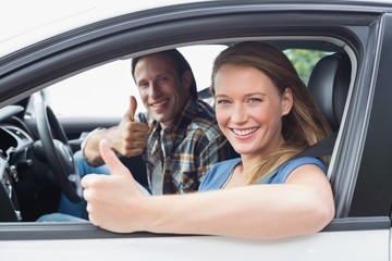 Couple smiling at the camera with thumbs up