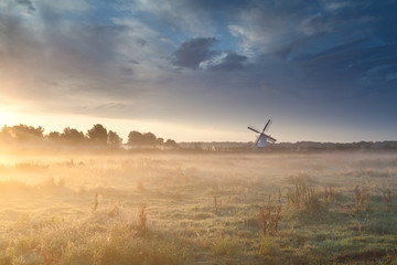 Fototapeta na wymiar windmill in summer mist at sunrise