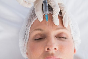 Woman receiving cosmetic injection on her forehead