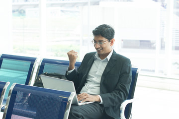 Asian Indian business man waiting his flight at airport, sitting