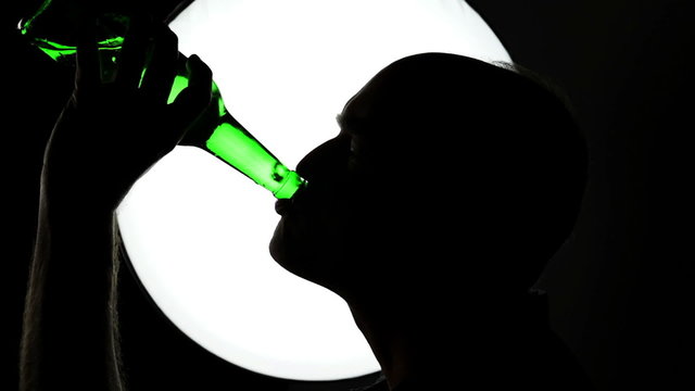 Middle-aged man is drinking alcohol - backlit