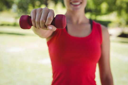 Fit woman lifting dumbbell in park