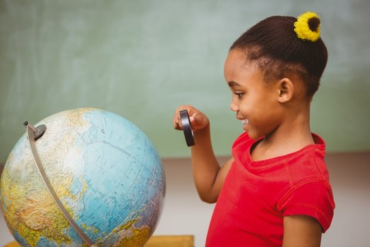 Girl Looking At Globe Through Magnifying Glass