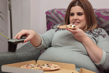 Woman eating pizza and watching tv on the couch