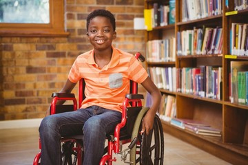 Portrait of boy sitting in wheelchair at library