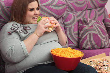Sedentary woman eating fast food on the couch