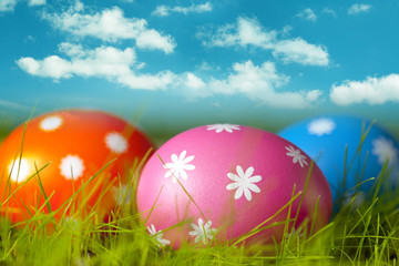 Colored Easter eggs on the grass and blue sky background