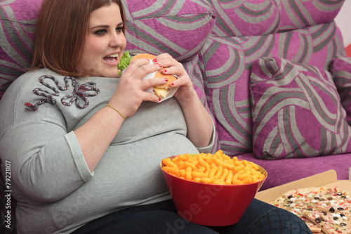 Sedentary Woman Eating Fast Food On The Couch Stock Photo And Royalty