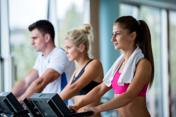friends  exercising on a treadmill at the bright modern gym