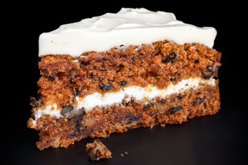 Slice of carrot cake with rich frosting. Isolated on black.