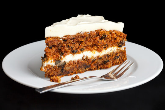 Slice of carrot cake with rich frosting. On plate.