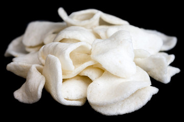 Pile of prawn crackers on black.
