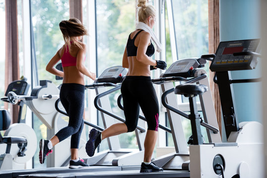 friends  exercising on a treadmill at the bright modern gym