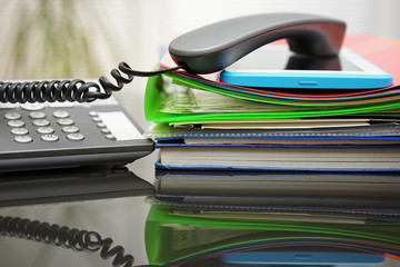 telephone handset and tablet pc on top of the documentation in o