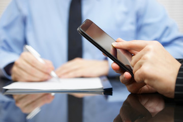 businesswoman is using mobile smart phone and businessman in bac