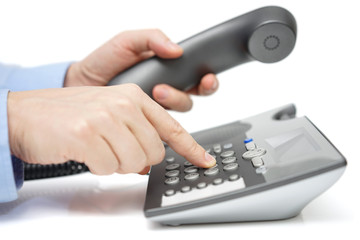 Businessman is dialing telephone number with handset in hand