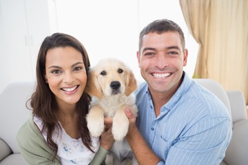 Happy couple holding puppy at home