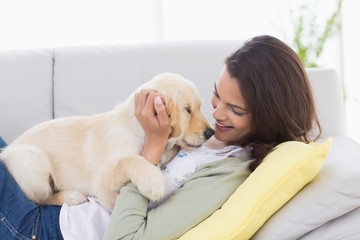 Woman playing with puppy while lying on sofa