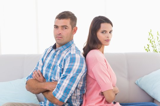 Angry couple sitting arms crossed on sofa