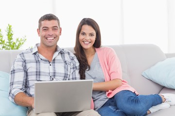 Happy couple with laptop on sofa