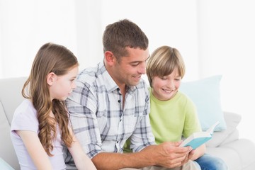 Man telling story to children while sitting on sofa