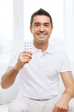 happy man showing pack of pills at home