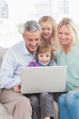 Fototapeta na wymiar Family of four using laptop