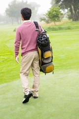 Fototapeta premium Golfer walking away holding golf bag