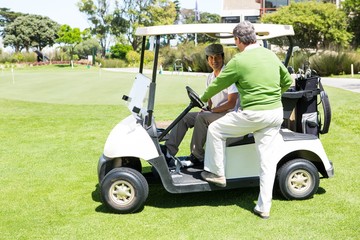 Happy golfing friends setting out on buggy