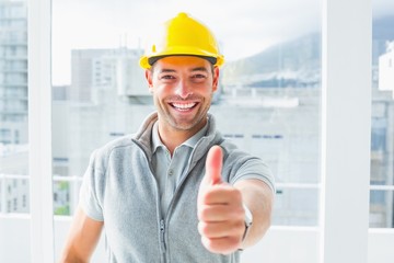 Manual worker gesturing thumbs up in building - obrazy, fototapety, plakaty