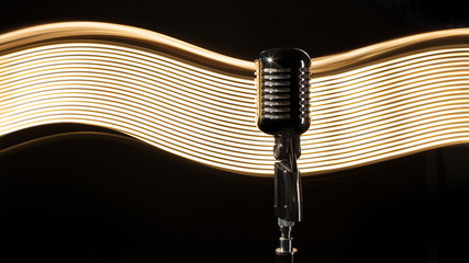 Vintage retro microphone on the black background with light wave