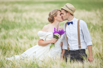 Young wedding couple walking on field.